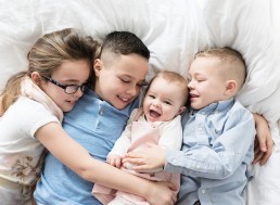 4 siblings lying on bed