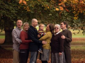 family standing in autumn leaves