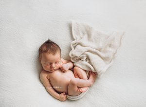 newborn baby lying on blanket