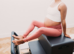 pregnant person on reformer pilates machine